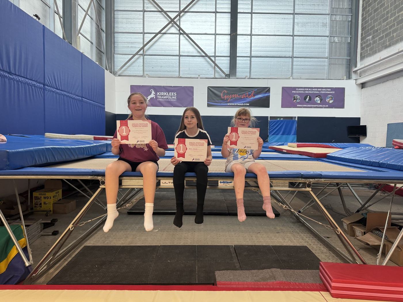 Three young KTGA gymnasts proudly holding their certificates