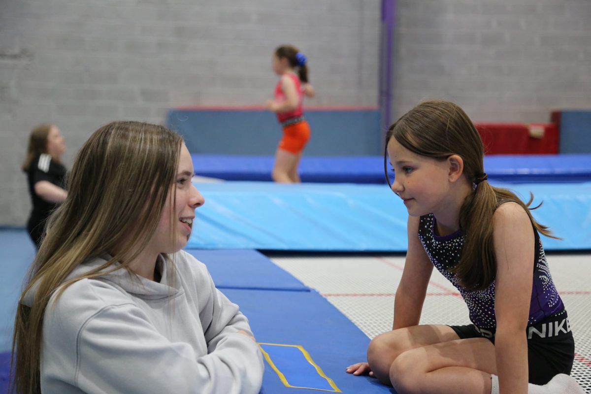 A coach chatting with a young gymnast on the trampoline