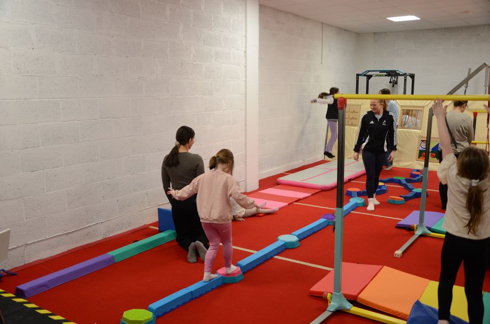 Young children playing on beams and soft-play equipment in the KTGA gym