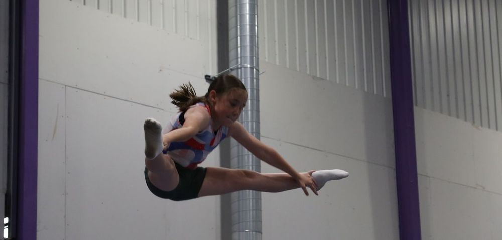 A gymnast in a mid-air straddle jump