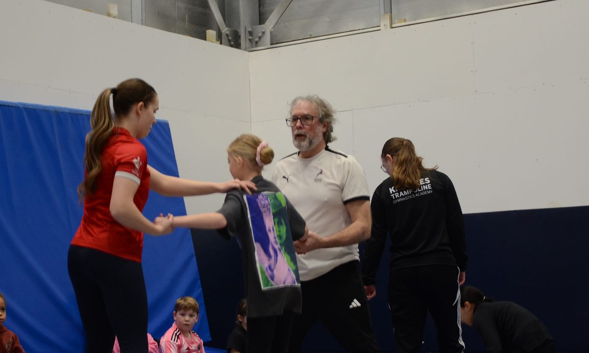 Older gymnasts and coaches working together on the trampolines in a training session