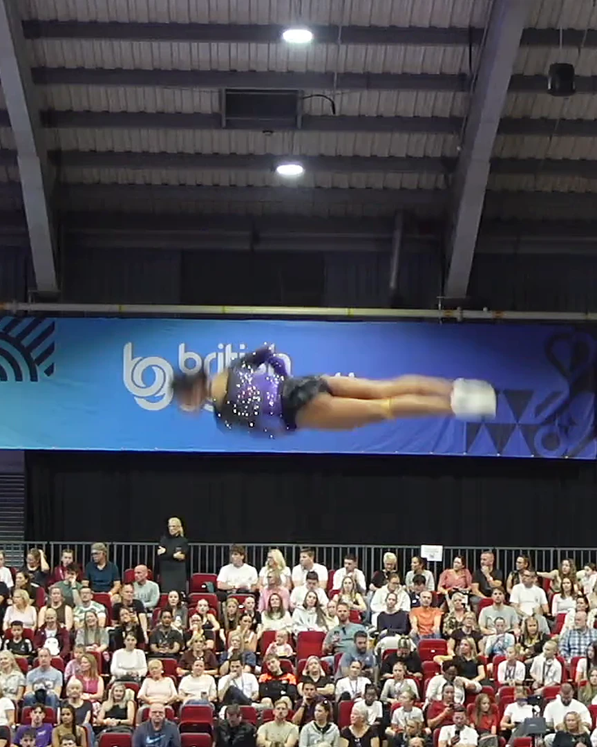 A KTGA athlete mid-routine, high above the trampoline at a gymnastics competition